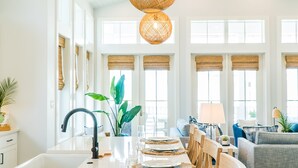Una cocina amplia con una isla grande, sillas de madera y una mesa de comedor preparada para seis comensales.