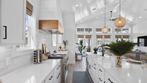 Una cocina moderna con armarios blancos, una isla central e iluminación colgante.