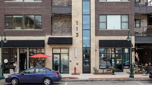 A multi-story building with a brick facade, numbered 113, featuring a central glass entrance, outdoor seating, and a visible storefront. - Park 201 Downtown in the Heart of Traverse City (Traverse City)