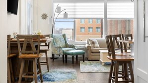 A modern living room with a dining area, large windows, and a view of a building outside. - Park 201 Downtown in the Heart of Traverse City (Traverse City)
