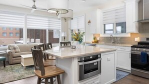 A modern kitchen with a central island, stainless steel appliances, and white cabinetry. - Park 201 Downtown in the Heart of Traverse City (Traverse City)