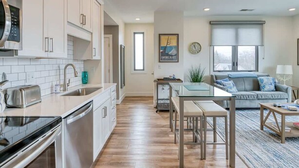 A modern kitchen with white cabinets, stainless steel appliances, and a glass dining table.