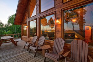 En träveranda med Adirondack-stolar och ett picknickbord.