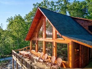 Enjoy outdoor dining or relaxation on the deck with comfortable seating and lush green surroundings.