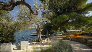 A stone pathway leading to outdoor seating with a view of the sea and boats. - Private waterfront villa with pool and two private beaches (geni)