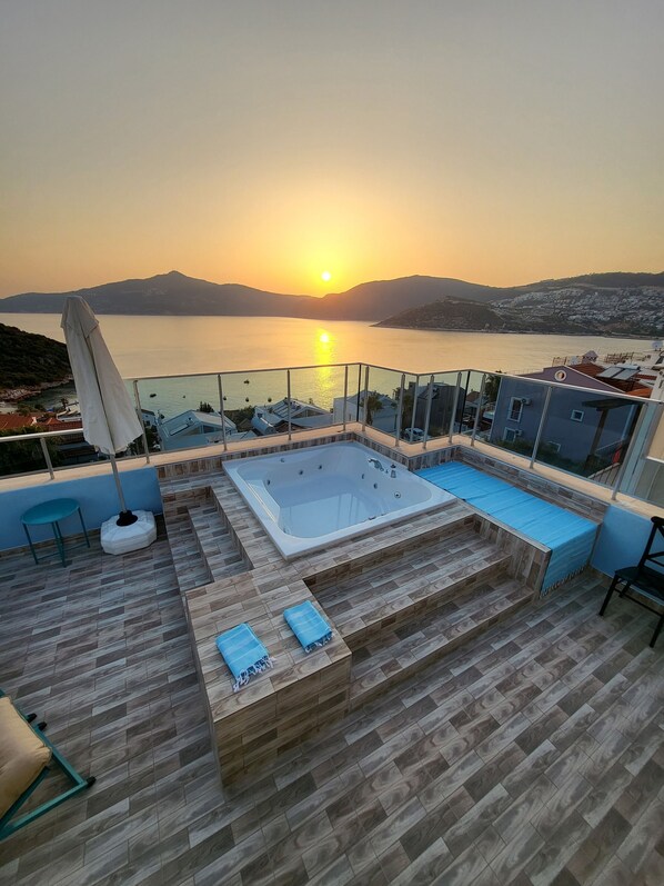Enjoy breathtaking views of the lake from this rooftop terrace, featuring a hot tub, seating area, and table.
