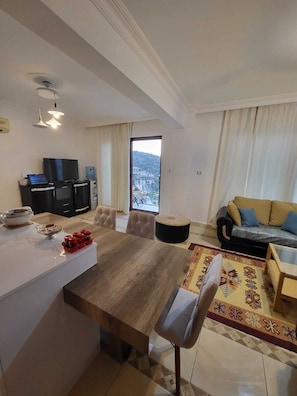 Relax in this stylish living space with a dining area, flat-screen TV, and sofa, offering a mountain view.