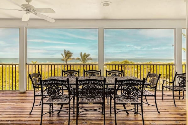 Relax in a covered outdoor seating area with ocean views and comfortable seating.