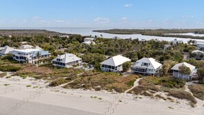 En kystejendom med flere strandhuse, en sandstrand og udsigt over havet.