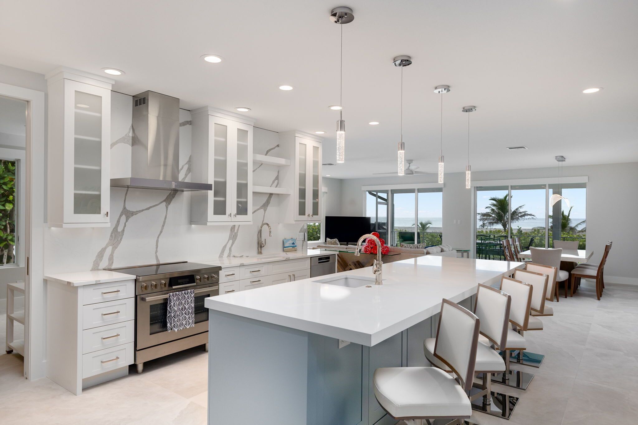 A modern kitchen with white cabinetry, a central island, and a large window overlooking a scenic view.