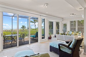 A spacious balcony with a view of the ocean, a dining area with outdoor furniture, and a seating area with a sofa and chairs.
