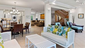 Ein modernes Wohnzimmer mit einer Couch, einem Esstisch, Stühlen und einer Küche im Hintergrund.