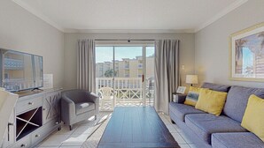Ett modernt hotellrum med en balkong, en soffa, en TV och ett skrivbord.