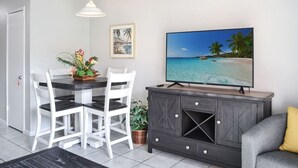 En matplats med ett bord, stolar, en tv och ett skåp.
