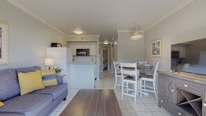 Ett modernt vardagsrum med en soffa, ett matbord och ett köksområde.