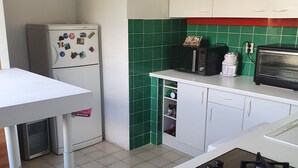 A compact kitchen with a white refrigerator, a microwave, a toaster, and a gas stove.