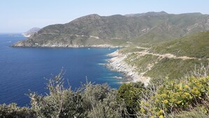A coastal landscape with a clear view of the sea and mountains.