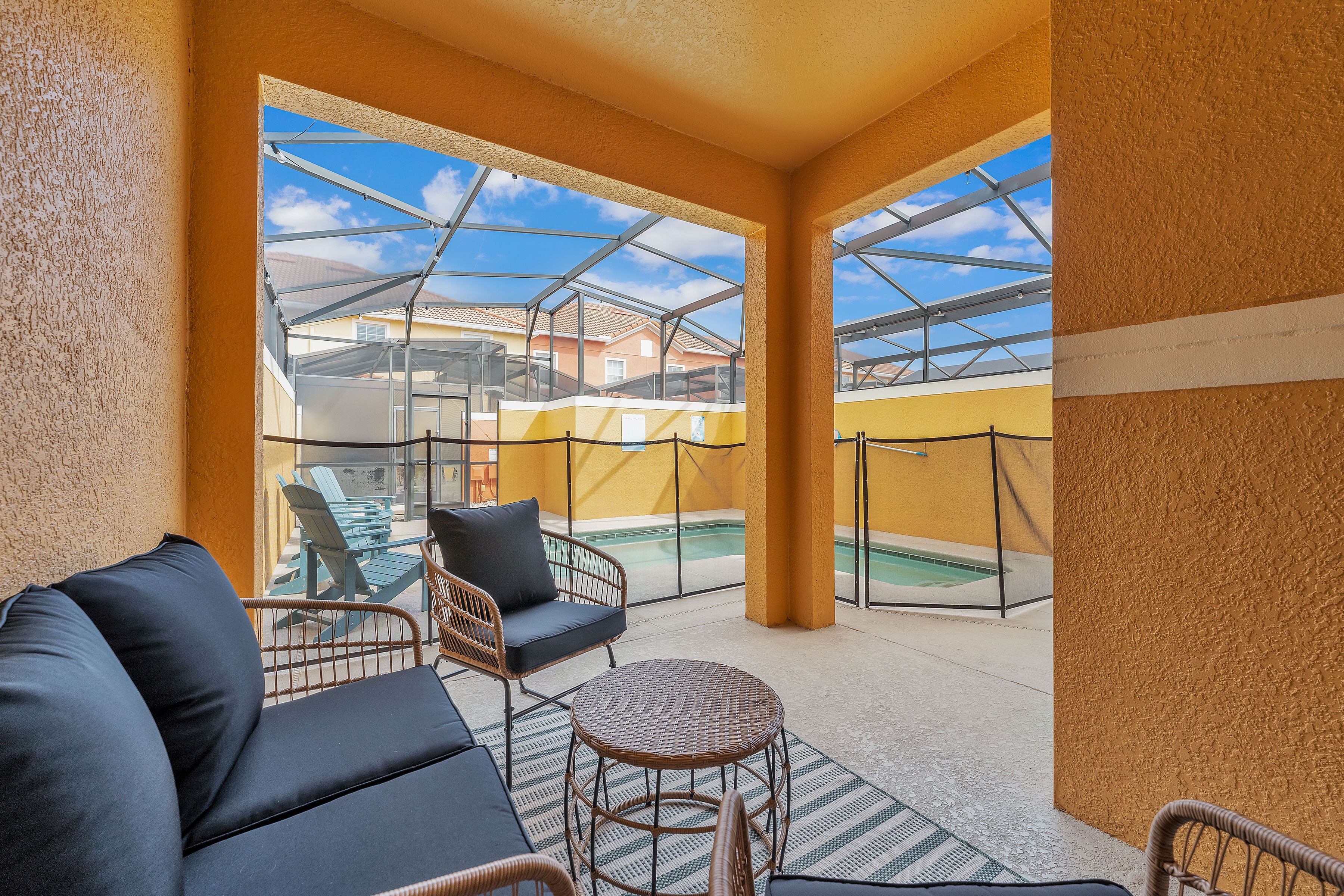A covered outdoor seating area with a glass enclosure, a pool, and a view of neighboring buildings.