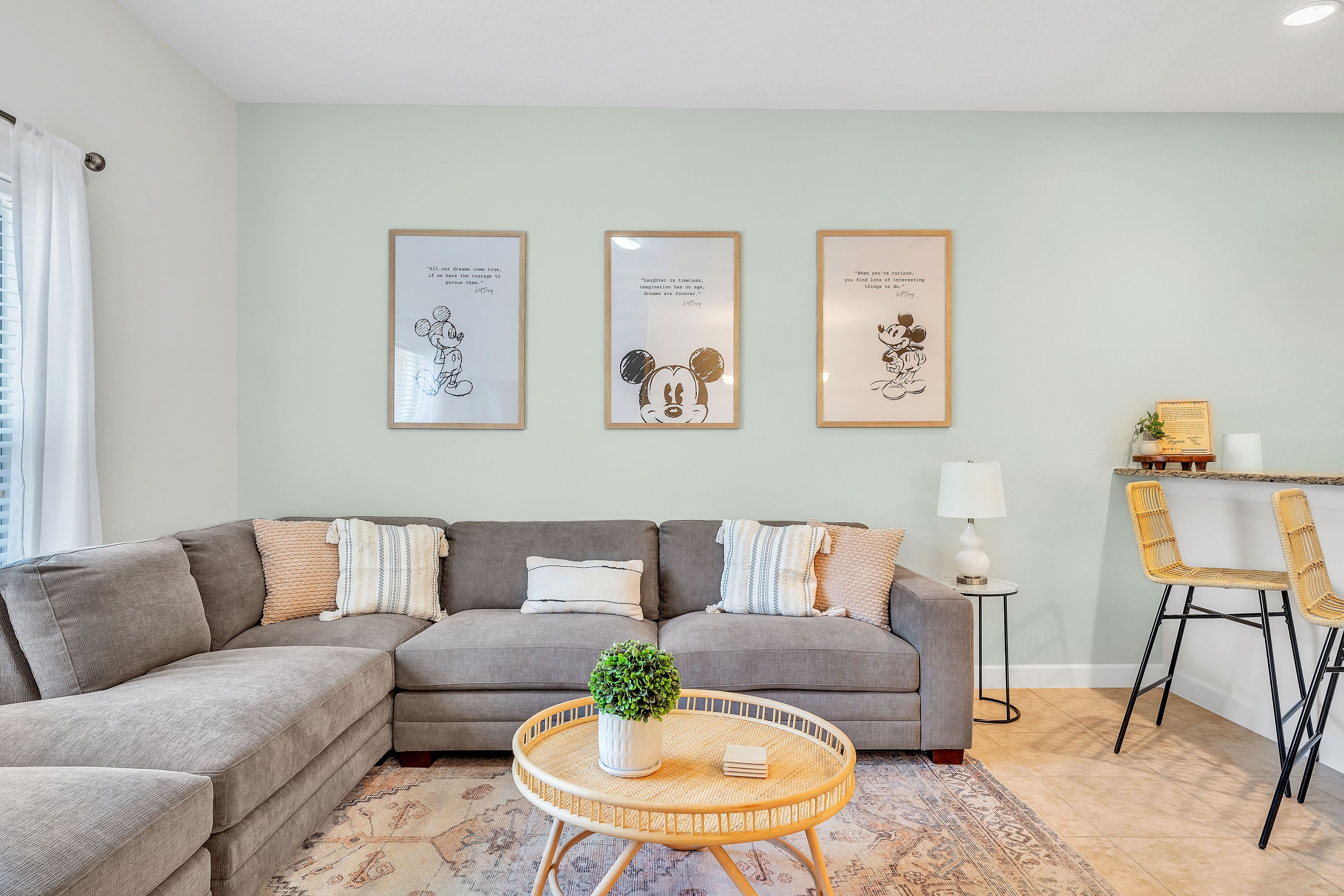 A modern living room with a grey sectional sofa, a round coffee table with a plant, and framed inspirational quotes on the wall.