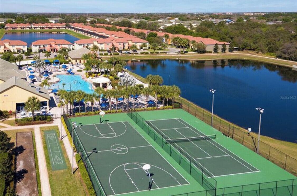 Vue aérienne d’un complexe hôtelier doté d’une piscine, de courts de tennis et d’un lac.