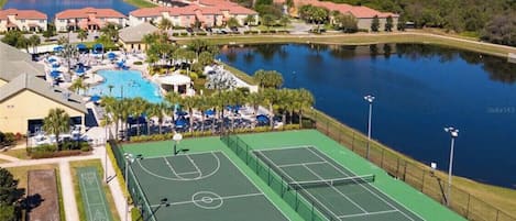 Vue aérienne d’un complexe hôtelier doté d’une piscine, de courts de tennis et d’un lac.