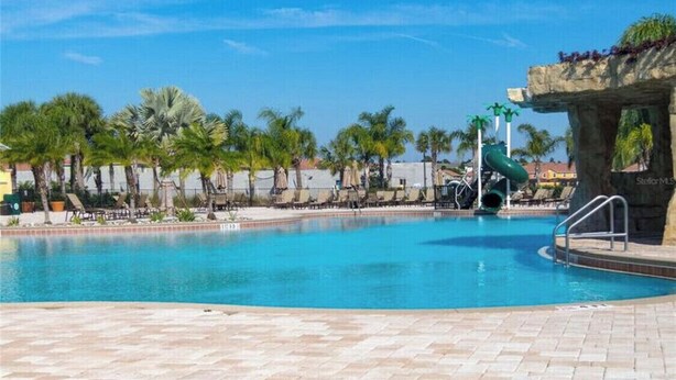 Una piscina con sillas de descanso y palmeras.