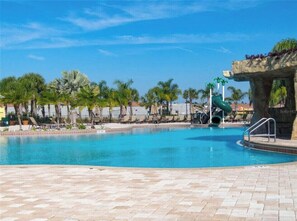 A swimming pool with lounge chairs and palm trees.