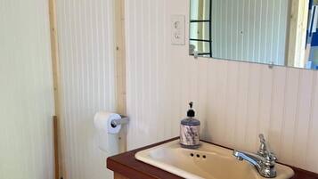 Une salle de bain avec un meuble-lavabo en bois, un évier, un miroir et des toilettes.