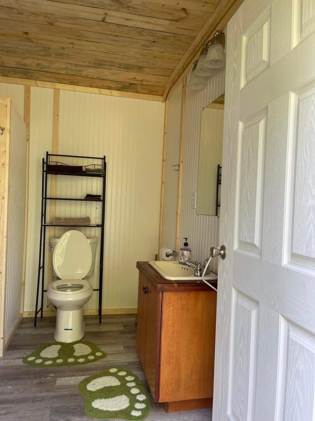 A compact bathroom with a toilet, sink, and wooden cabinet.