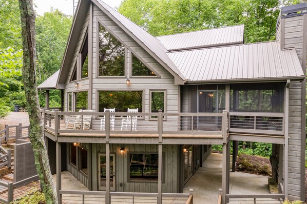 A multi-level wooden cabin with a balcony, large windows, and a deck area.