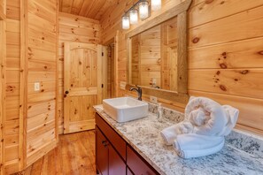 A wooden cabin bathroom with a sink, mirror, and towel.