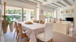 A modern dining area with a large table, wicker chairs, and a view of the outdoors.