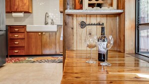 A wooden table with two wine glasses and a bottle of wine. - Lake access cabin near trails and spring (Black Diamond)