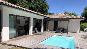 Une maison moderne dotée d’une piscine, d’une terrasse en bois et d’un patio couvert.