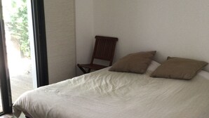 Une chambre à coucher avec un lit, des oreillers, une chaise et une vue sur la verdure.