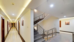 A hotel corridor with a staircase and a long hallway with doors. - La Sara Gateway (Anekal)