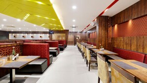 A restaurant with booths and tables, wooden paneling, and a patterned wall. - La Sara Gateway (Anekal)