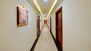 A long, well-lit hallway with doors on both sides, a tiled floor, and a ceiling light. - La Sara Gateway (Anekal)