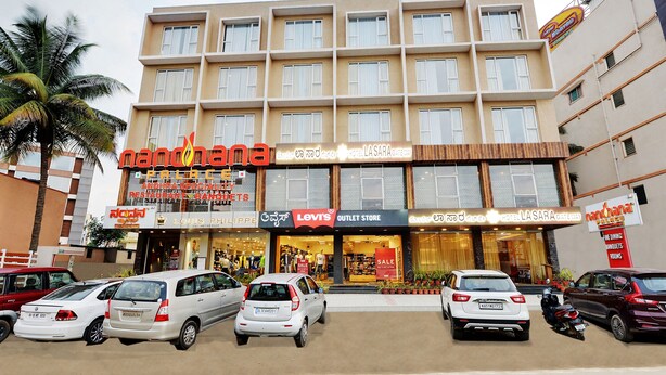 A hotel with multiple floors, a prominent 'Levi's Outlet Store' sign, and several parked cars in front. - La Sara Gateway (Anekal)