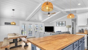 A modern kitchen with a wooden island, grey cabinets, and pendant lighting. - Sawyer's Shore Shack: Spacious, Modern Second Row Beach Home on the West End (Oak Island)