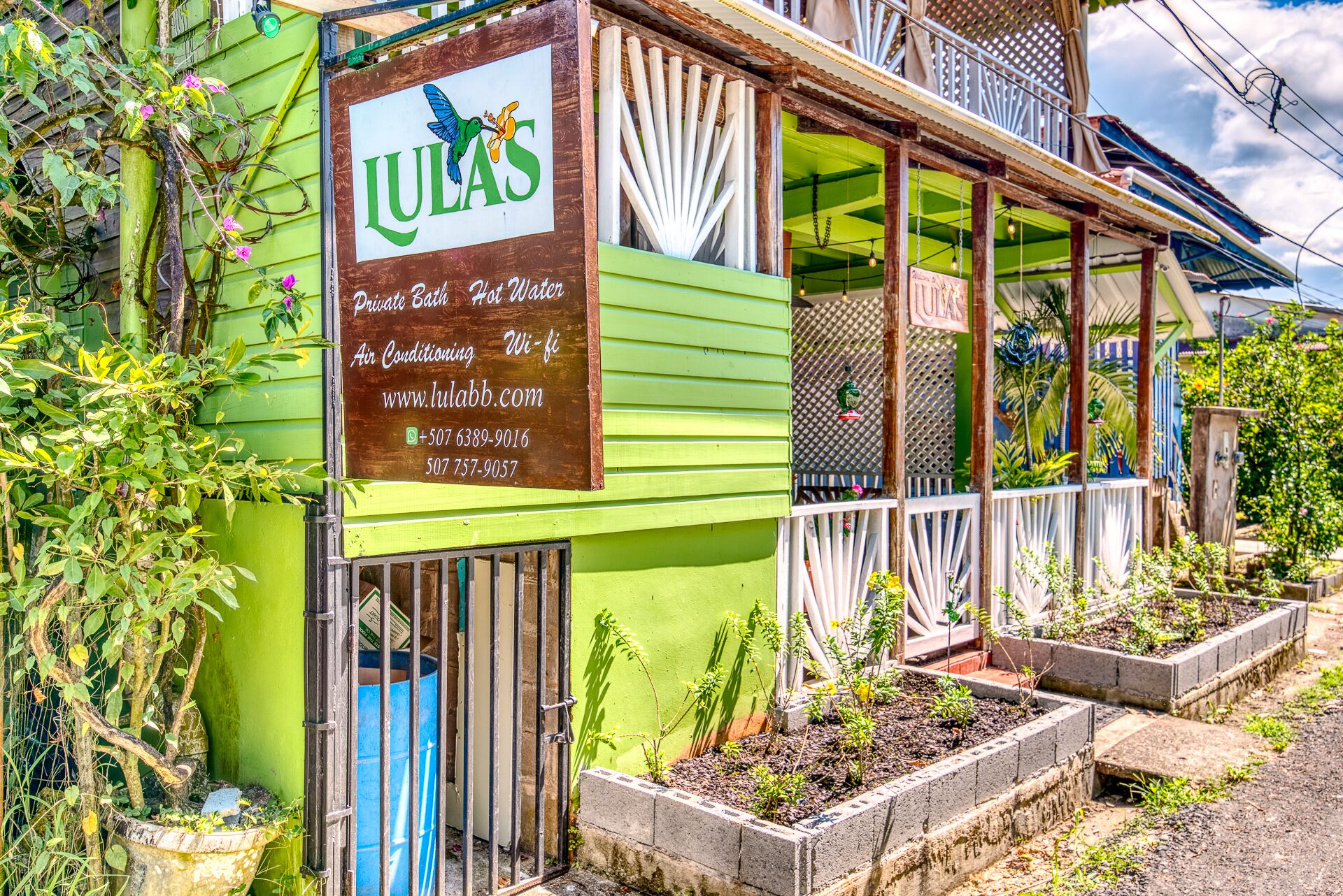 A green building with a sign advertising LULAS services, including private bath, hot water, air conditioning, and Wi-Fi.