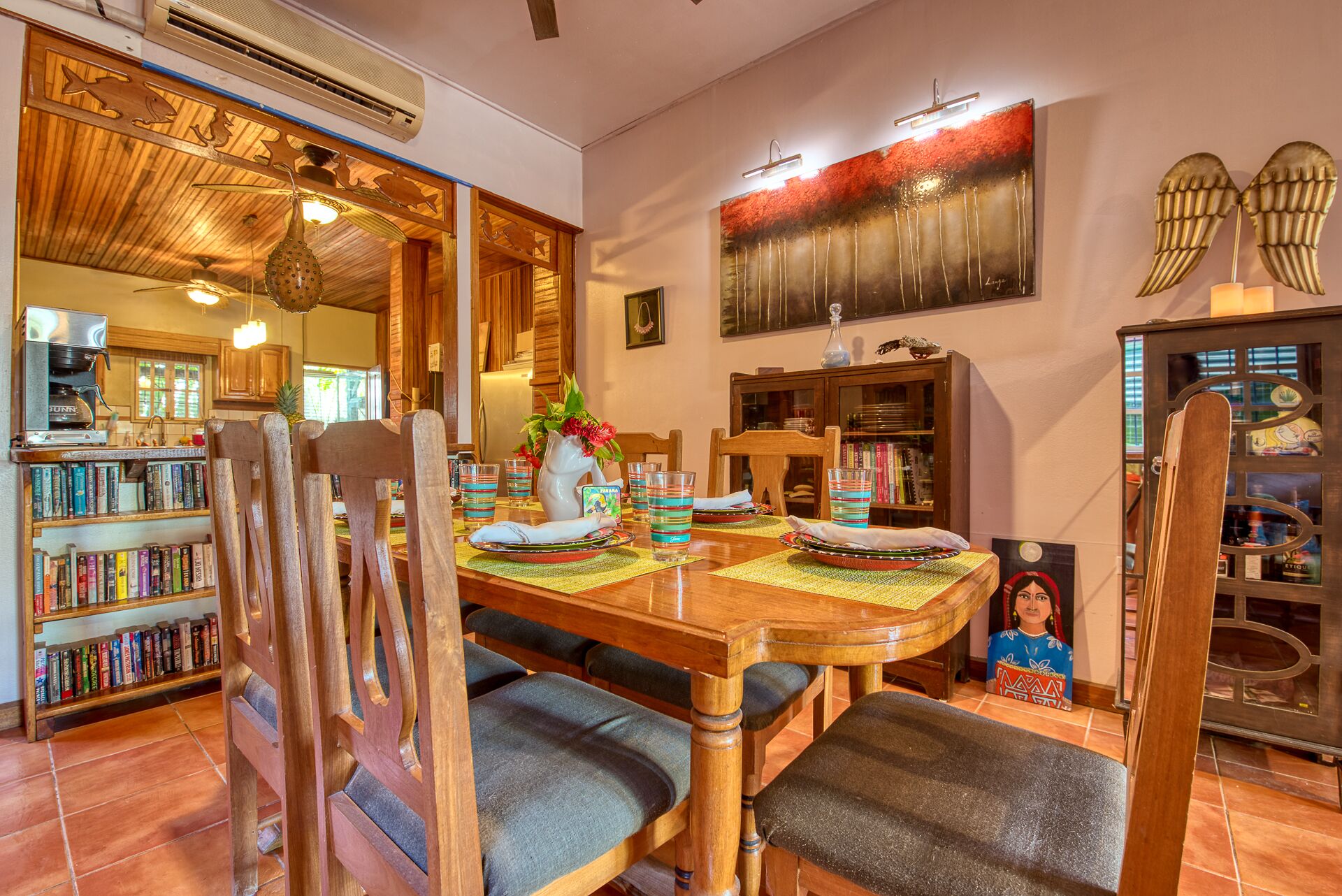 A dining area with a wooden table, chairs, and a bookshelf filled with books.