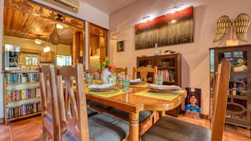 A dining area with a wooden table, chairs, and a bookshelf filled with books.