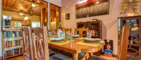 A dining area with a wooden table, chairs, and a bookshelf filled with books.