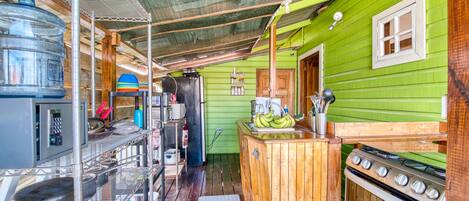 A compact kitchen with a green exterior, a wooden counter, a stove, and a water dispenser.