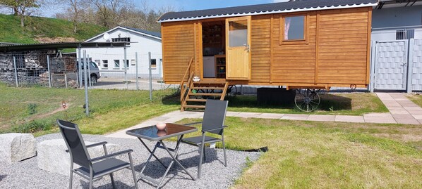 Une cabane en bois avec une véranda et une table entourée de chaises.