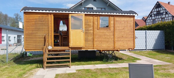 Eine Holzhütte mit einer Haustür, einer kleinen Veranda und einem Fenster.