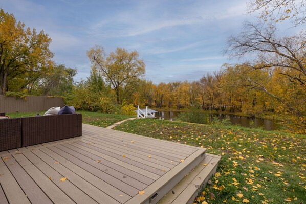 A wooden deck with a built-in seating area overlooking a pond surrounded by autumn foliage. - River Rambler (La Crosse)