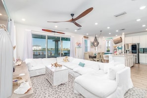 A spacious living area with a white sofa set, a wooden coffee table, and a ceiling fan.
