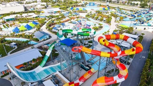 Ein Wasserpark mit mehreren Rutschen und Pools, umgeben von Gebäuden und Grünflächen.